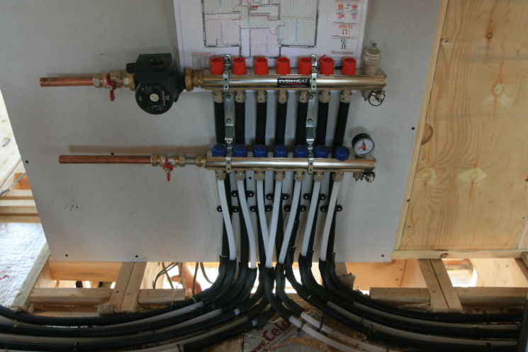 The brass manifold features multiple connected pipes, each with red or blue valve caps for hot and cold water control