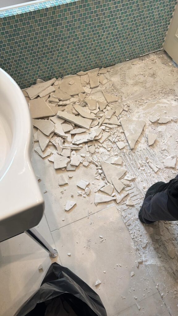 Broken tiles scattered across the floor, showing renovation work in progress
